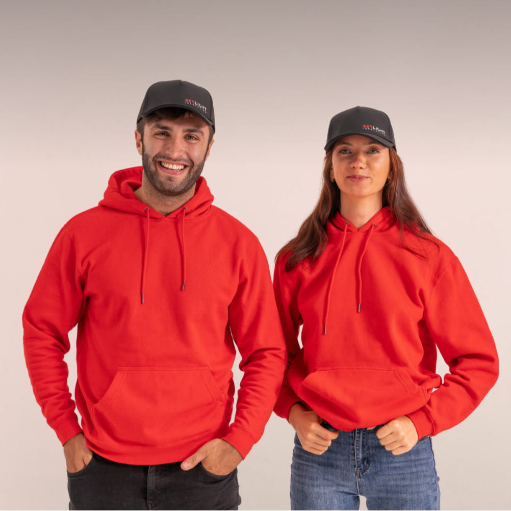 Two people wearing red hoodies and black caps on a plain background