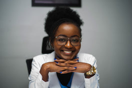 Celestine Gitau, certified trichologist for RedLight Innovation, wearing a white clinical coat in her consultation room